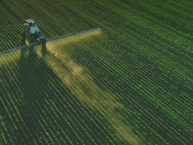 Tractor spraying pesticide on field